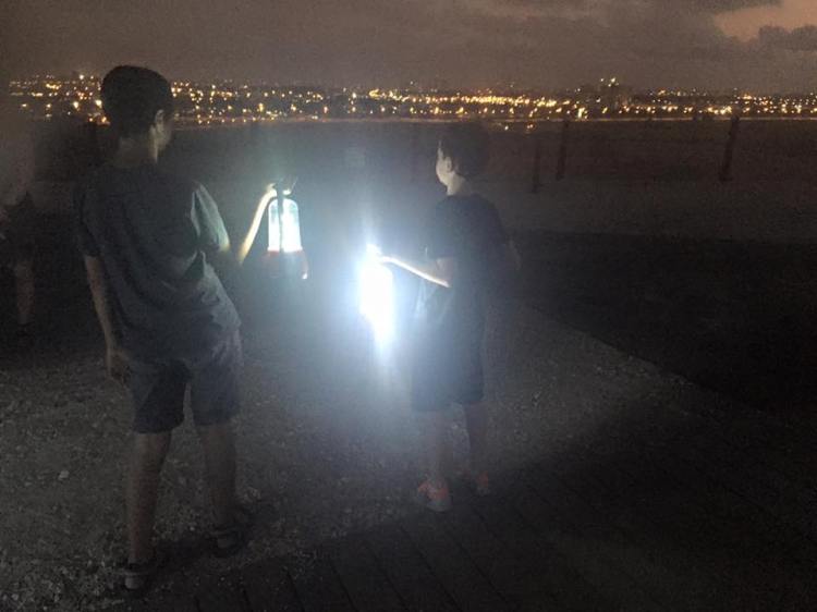 מחזיקים עששיות על רקע אורות גוש דן